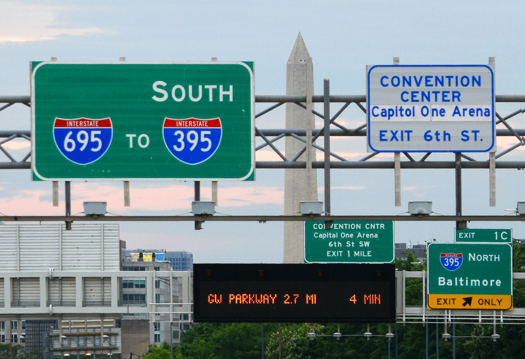 Overhead highway exit signage stacked across several lanes
